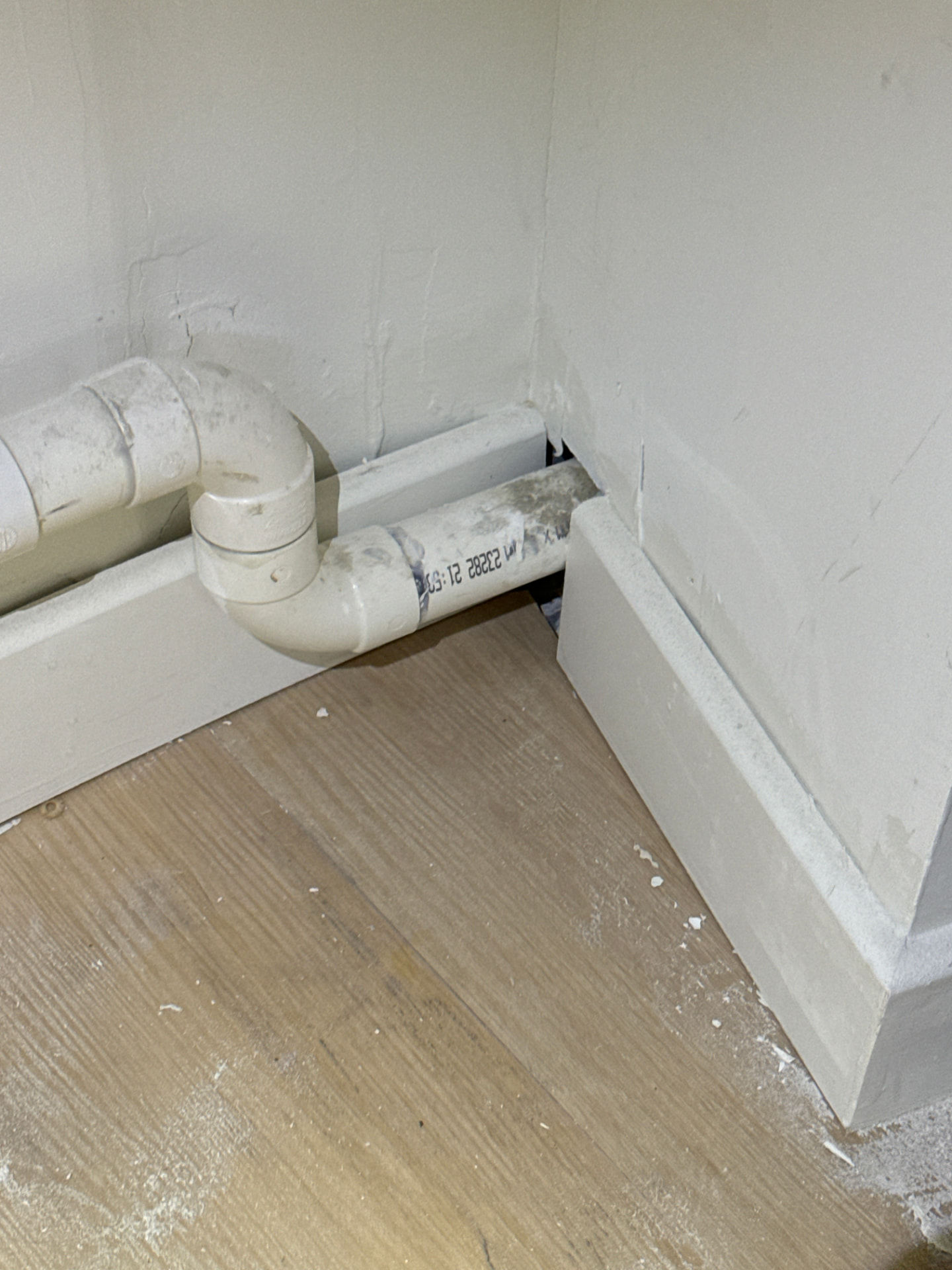 Incomplete boxing and poor finishing around service pipework at skirting level