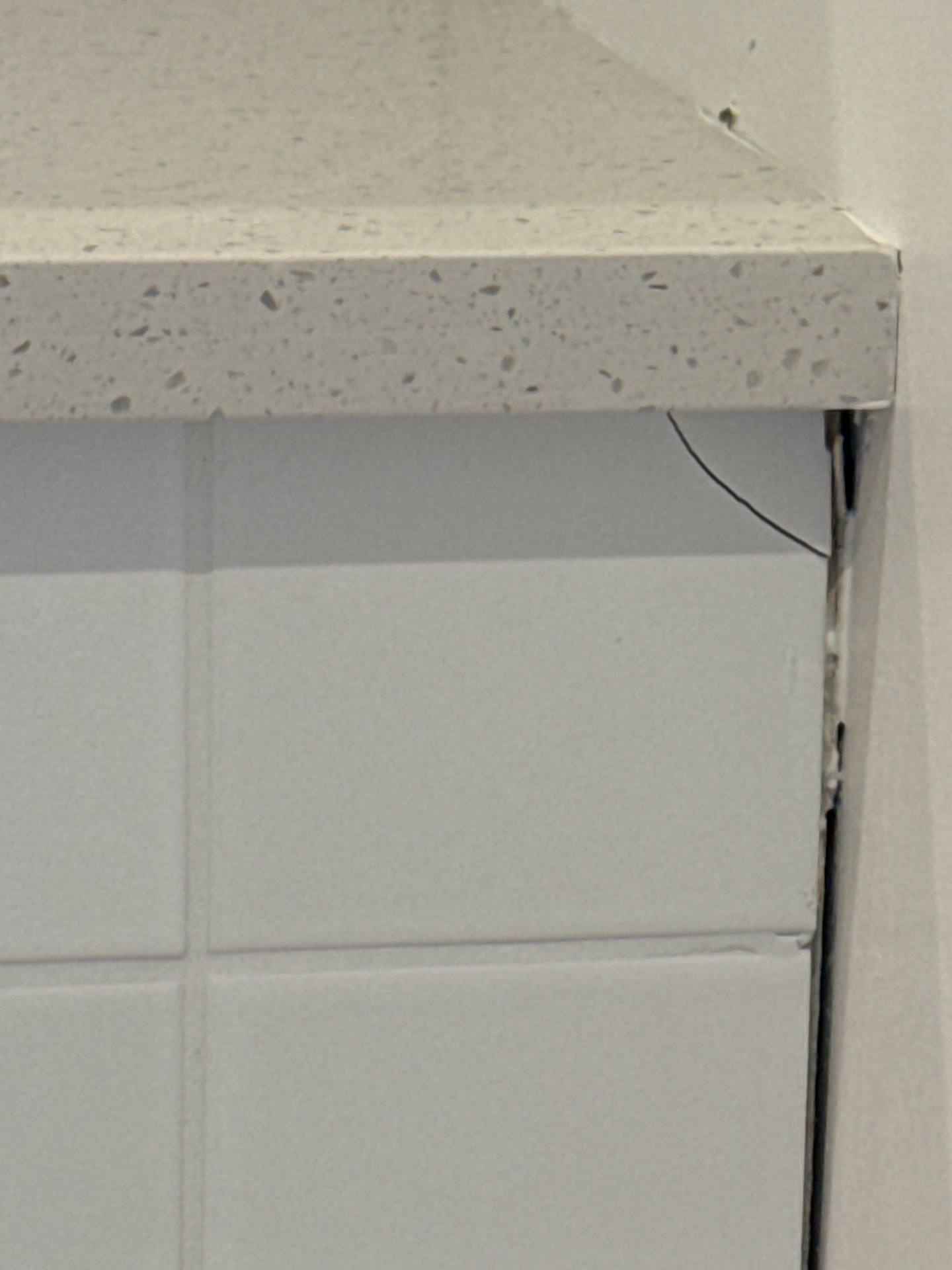 Cracked tile and unsealed gap between a kitchen worktop, tiled splashback and adjoining wall