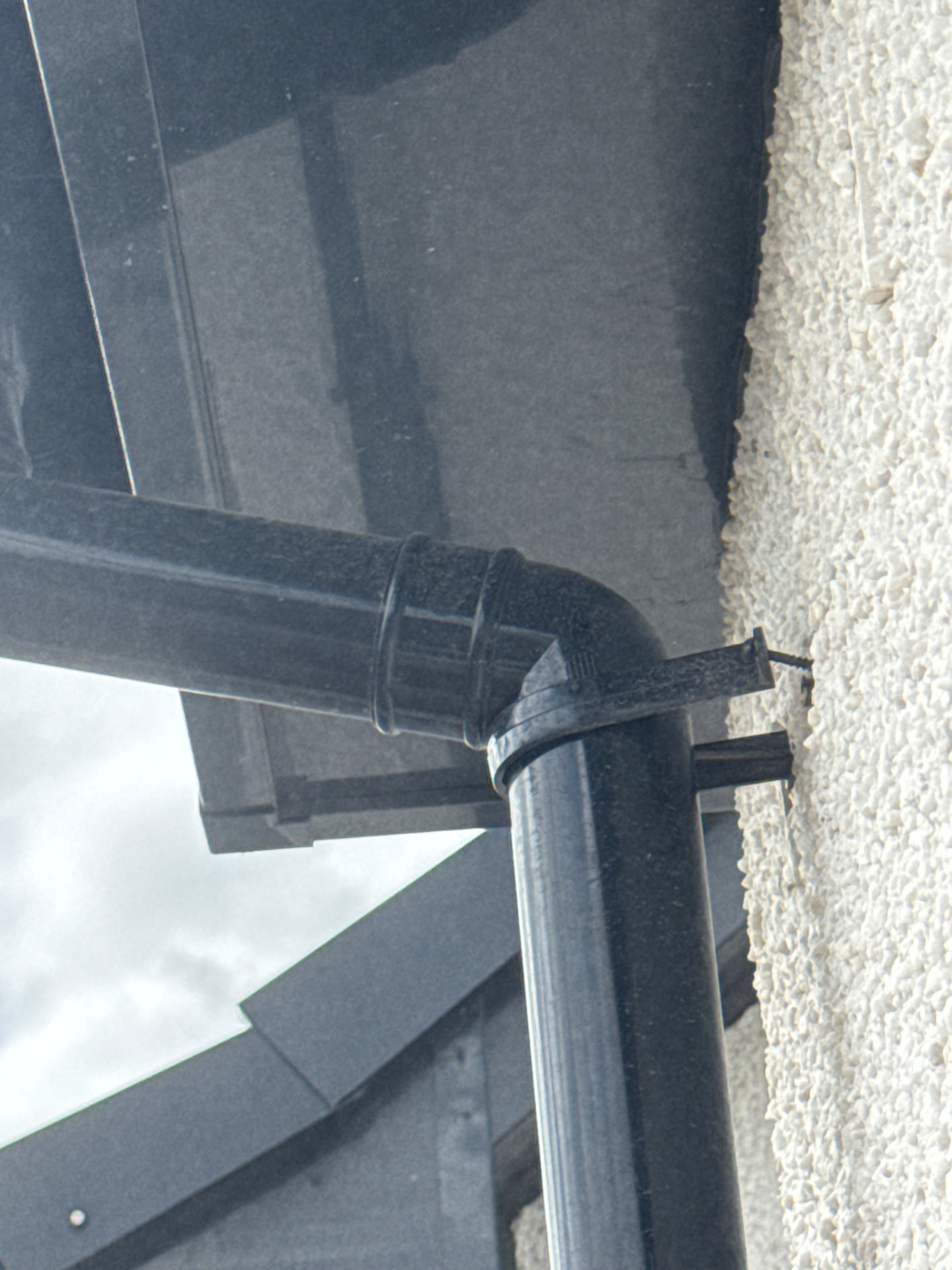 Loose downpipe bracket fixing recorded on the external wall of a new build home