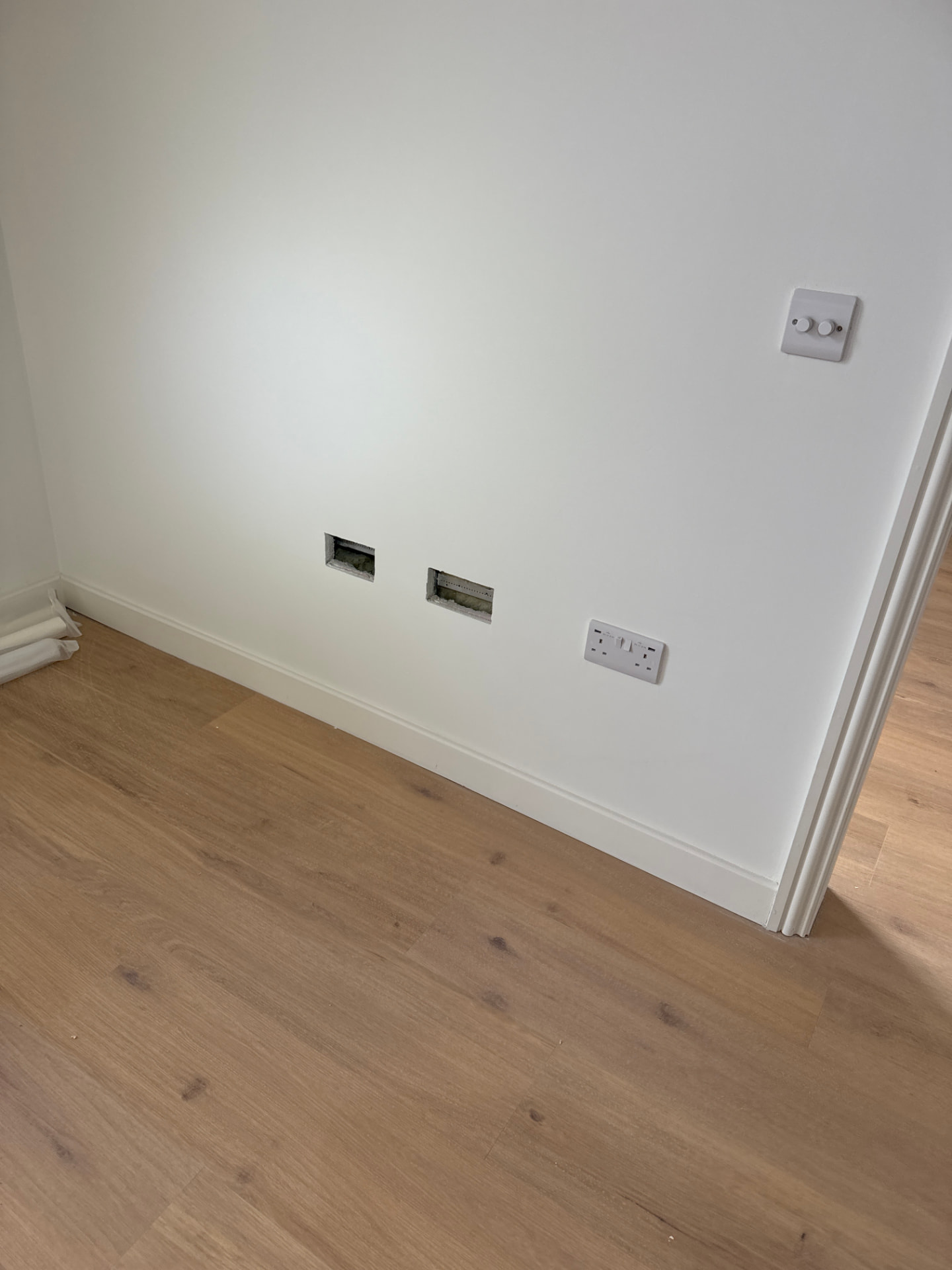 Missing TV and data faceplates left unfitted on a living room wall in a new build home