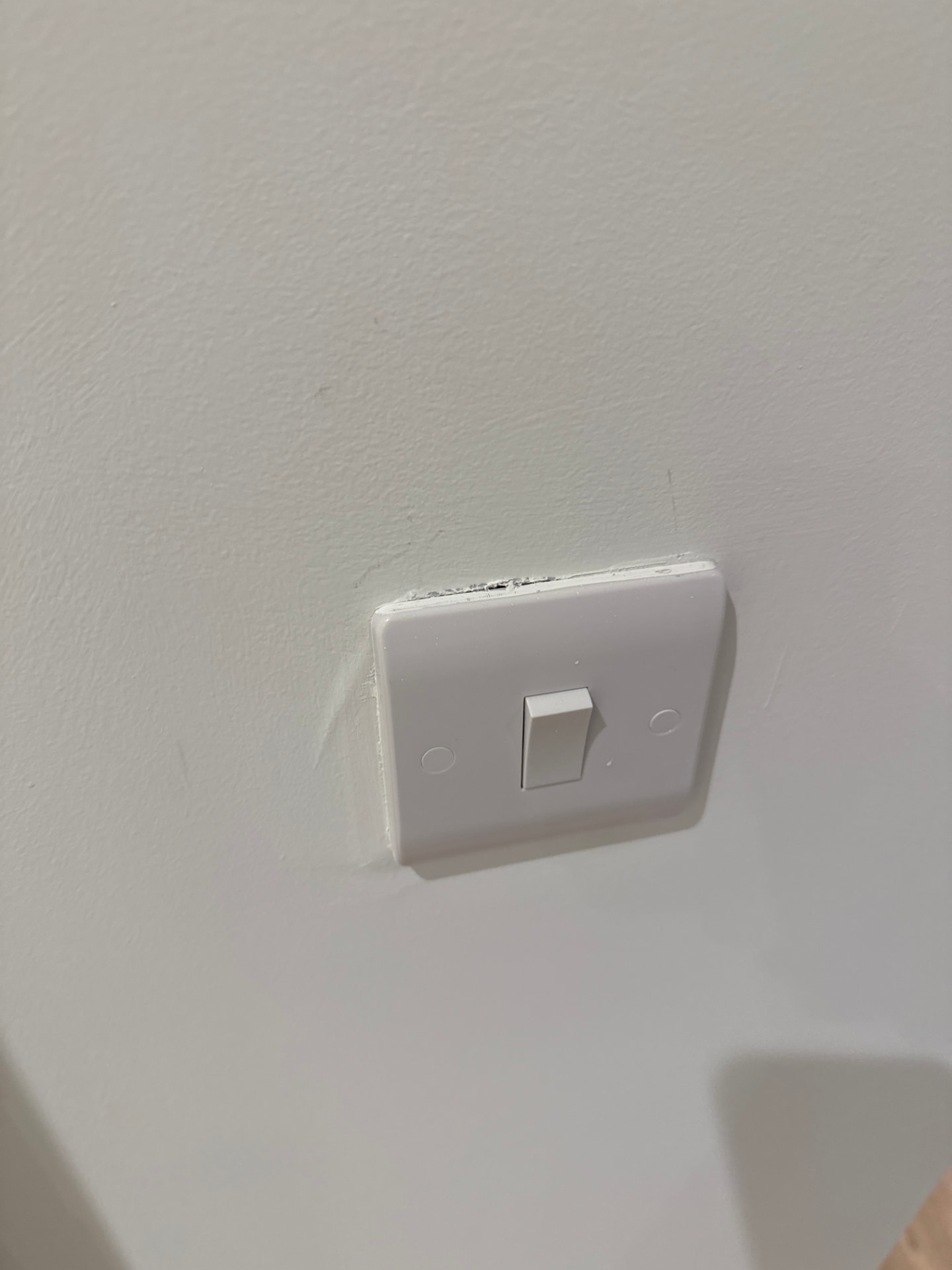Poorly finished light switch with damaged paintwork recorded during a snagging inspection